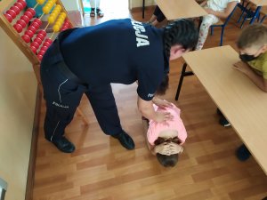 Policjantka wspólnie z uczennicą pokazują pozycję na żółwia