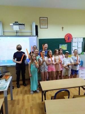 Wspólne zdjęcie policjantki z uczniami jednej z klas. Wszyscy trzymają w rękach odblaskowe opaski