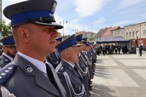 Plac Wolności w Sępólnie Krajeńskim. Uroczysta zbiórka z okazji Święta Policji. Od lewej strony widać profile twarzy policjantów ustawionych w rzędzie.