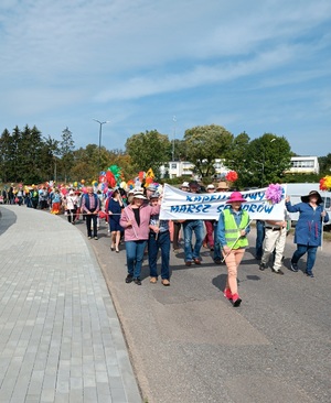 Uczestnicy marszu idą ulicą przy stadionie miejskim. W rękach trzymają transparenty.