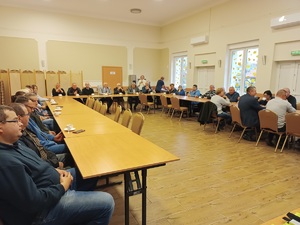 Sala konferencyjna w Gminnym Domu Kultury w Sośnie. Uczestnicy debaty siedzą przy stołach ułożonych w literę U.