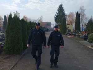 Policjanci patrolują rejon cmentarza w Sępólnie Krajeńskim. Dookoła nich groby zmarłych.