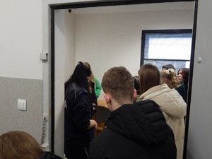 Policjantka oprowadza uczniów po celi dla osób zatrzymanych