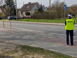 Policjant stoi przy ulicy i kontroluje ruch drogowy