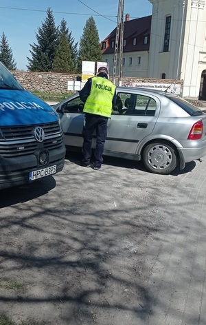 Policjant zatrzymał pojazd do kontroli. Po lewej stronie zdjęcia widać policyjny radiowóz