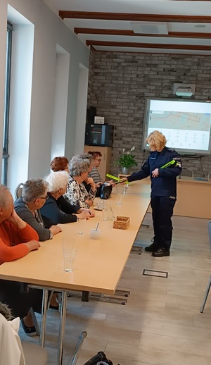 Policjantka rozdaje odblaski uczestnikom klubu seniora