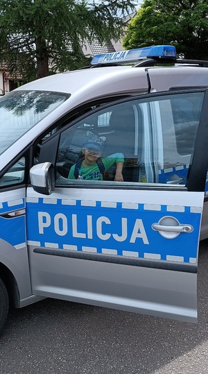Teren Szkoły podstawowej numer 1 w Sępólnie Krajeńskim. Dziewczynka siedzi za kierownicą radiowozu policyjnego.