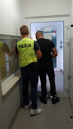 Policjant prowadzi zatrzymanego mężczyznę