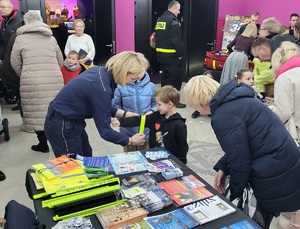 Policjantka zakłada chłopcu na rękę opaskę odblaskową.