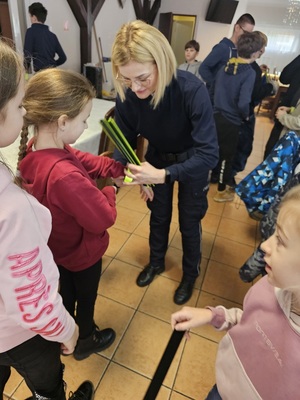 Policjantka wręcza uczestniczce półkolonii opaskę odblaskową