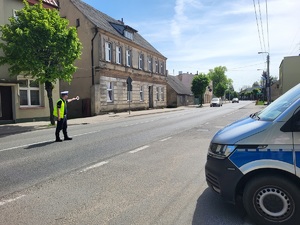 Policjant stoi na środku ulicy. Wydaje polecenie kierowcy pojazdu do zatrzymania się.