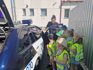 dzieci razem z policjantką oglądają radiowóz policyjny
