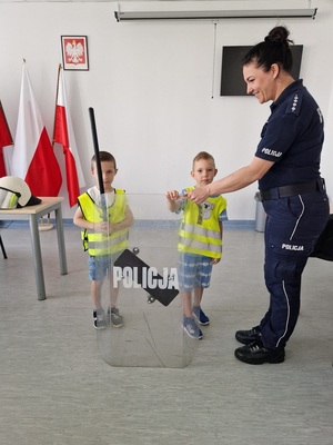 Policjantka pokazuje chłopcom policyjny sprzęt przeciwuderzeniowy
