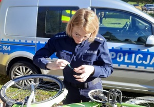 Policjantka przykleja naklejkę na oznakowany rower.