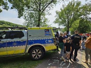 Policjanci i dzieci stoją przy radiowozie