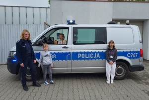 Wspólne zdjęcie dzieci przed radiowozem z policjantką