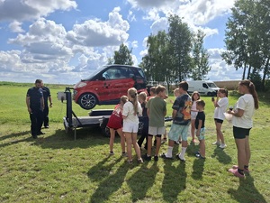 Policjanci oraz uczestnicy pikniku stoją przy symulatorze dachowania