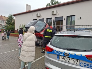 Policjantka stoi przy symulatorze dachowania. W tle widać policyjny radiowóz.