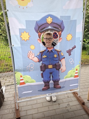 Dziecko pozuje do zdjęcia na tle planszy policjanta.