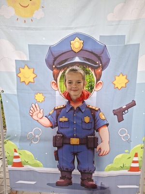 Dziewczynka pozuje do zdjęcia na tle planszy policjanta.