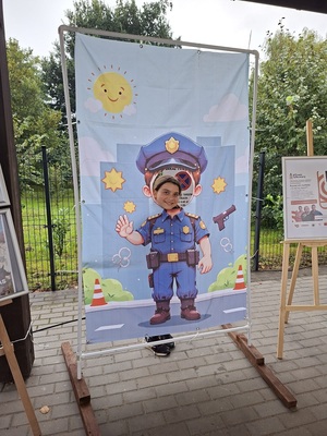 Dziecko pozuje do zdjęcia na tle planszy policjanta.