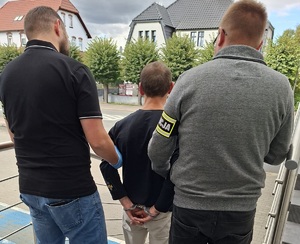 Policjanci prowadzą zatrzymanego