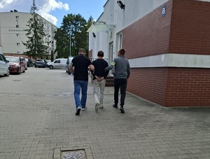 Policjanci prowadzą zatrzymanego