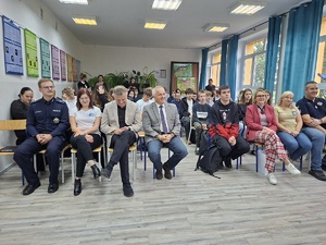 Oficjalne rozpoczęcie Dnia Promocji Zdrowia. Prelegenci siedzą razem z uczniami na sali lekcyjnej. Przemawia do nich na stojąco dyrektor szkoły.