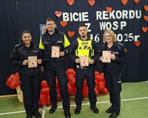 Wspólne zdjęcie policjantów na tle hasła akcji &quot; Bicie rekordu z WOŚP 16.X.2025&quot;