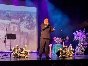 Sala kinowa w Centrum Kultury i Sztuki w Sępólnie Krajeńskim. Na scenie śpiewa policjant, a za jego plecami na sofie siedzą dwie policjantki oraz pracownik cywilny. W tle wyświetlany jest film promujący poszczególne gminy powiatu sępoleńskiego.