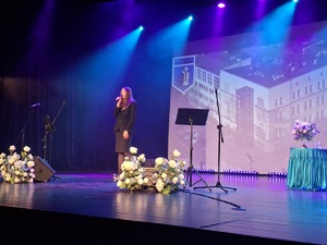 Sala kinowa w Centrum Kultury i Sztuki w Sępólnie Krajeńskim. Na scenie śpiewa młoda kobieta-wokalistka. W tle wyświetlany jest film promujący poszczególne gminy powiatu sępoleńskiego. Po bokach sceny  ustawione są banery promujące Komendę Powiatowa Policji w Sępólnie Krajeńskim oraz Niezależny Samorządny Związek Zawodowy Policjantów w Sępólnie Krajeńskim