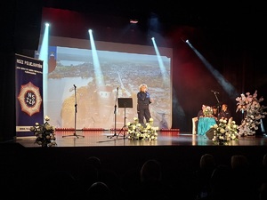 Sala kinowa w Centrum Kultury i Sztuki w Sępólnie Krajeńskim. Na scenie śpiewa policjantka z Chojnic, a za jej plecami na sofie siedzą dwie policjantki oraz pracownik cywilny. W tle wyświetlany jest film promujący poszczególne gminy powiatu sępoleńskiego. Po bokach sceny  ustawione są banery promujące Komendę Powiatowa Policji w Sępólnie Krajeńskim oraz Niezależny Samorządny Związek Zawodowy Policjantów w Sępólnie Krajeńskim