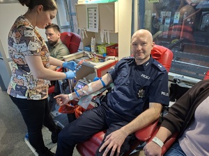 Na zdjęciu policjant w trakcie oddawania krwi