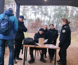 Uczestnicy konkursu stoją przy stoisku strzeleckim