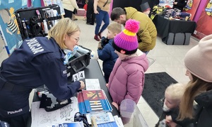 Policjantka rozmawia z dzieckiem przy stoisku profilaktyczno-promocyjnym podczas WOŚP.