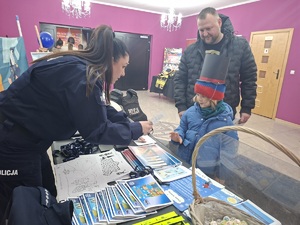 Policjantka rozmawia z dzieckiem przy stoisku profilaktyczno-promocyjnym podczas WOŚP.