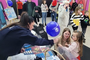Policjantka rozmawia z dzieckiem przy stoisku profilaktyczno-promocyjnym podczas WOŚP.