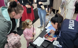Policjantka rozmawia z dzieckiem przy stoisku profilaktyczno-promocyjnym podczas WOŚP.