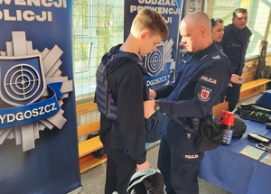 Drzwi otwarte w liceum ogólnokształcącym w Sępólnie Krajeńskim. Jeden z uczni przymierza sprzęt przeciwuderzeniowy. W tle widać ustawione policyjne rolapy.
