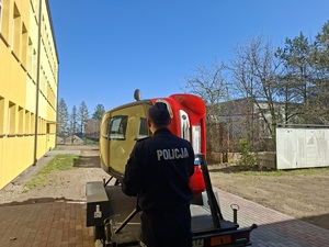 Policjant stoi przy symulatorze dachowania.