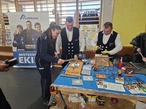 Policjantka stoi przy stoisku innych wystawców.