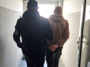 Policjant prowadzi zatrzymanego sprawcę przestępstw