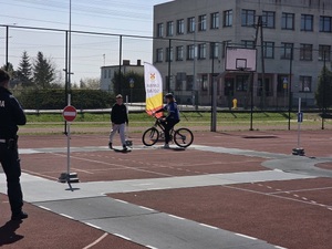 Na zdjęciu widać uczestnika turnieju w trakcie jazdy po wyznaczonym torze. Z lewej strony zdjęcia widać częściowo postać policjanta.