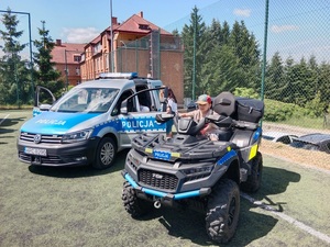 Policjanci na festynie w Kamieniu Krajeńskim wraz z uczestnikami. Dzieci pozują do zdjęć na quadzie.