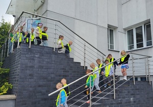 Przedszkolaki schodzą po schodach z budynku komendy