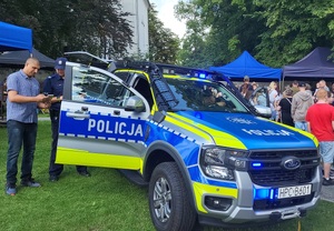 Uczestnik festynu stoi przy radiowozie policyjnym