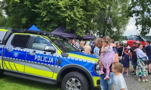 Uczestnicy stoją przy  radiowozie policyjnym